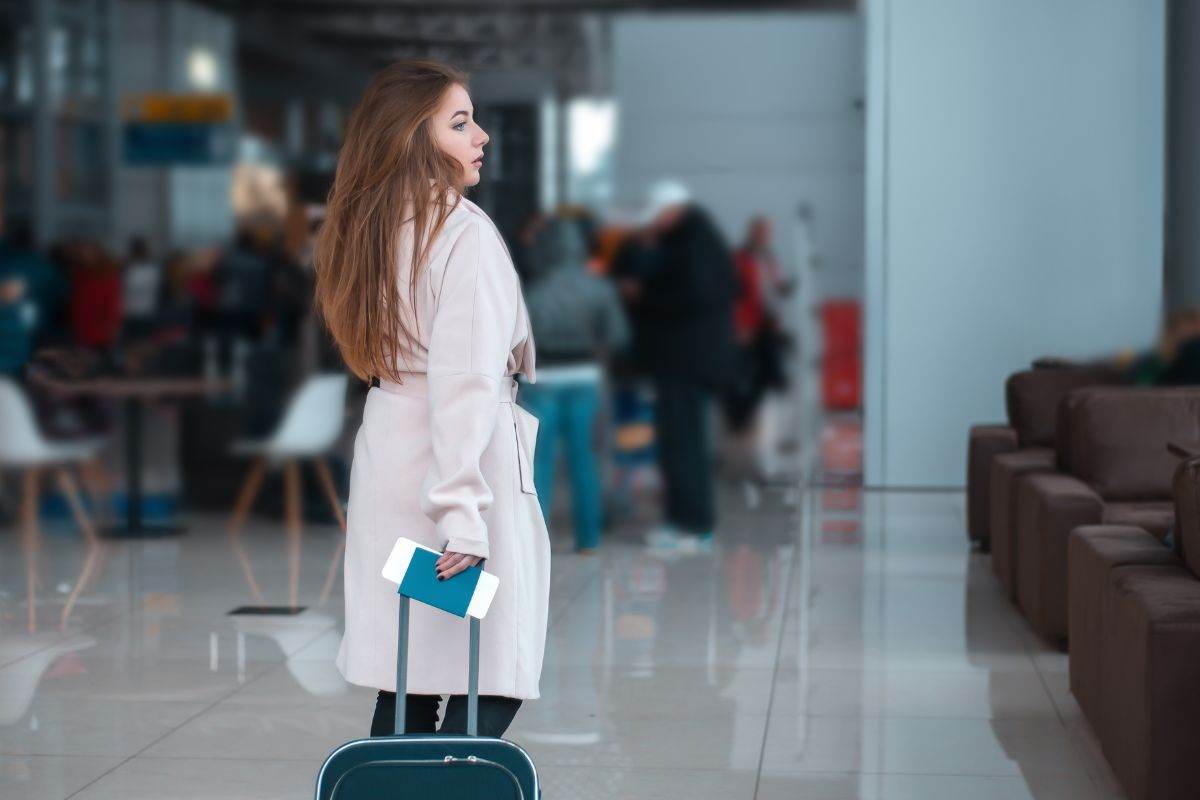 Ragazza in aeroporto con bagaglio a mano